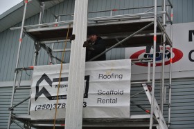 A worker for a contractor installs aluminium soffit material to the local curling club in Merritt BC